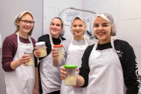 Vier Teenagerinnen präsentieren stolz ihre selbstgemachte Butter