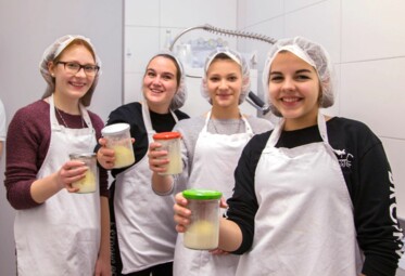 Vier Teenagerinnen präsentieren stolz ihre selbstgemachte Butter